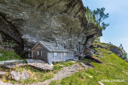 Die alte Farm Koldal mit den markanten Hütten unter dem Felsen (Hardangerfjord)