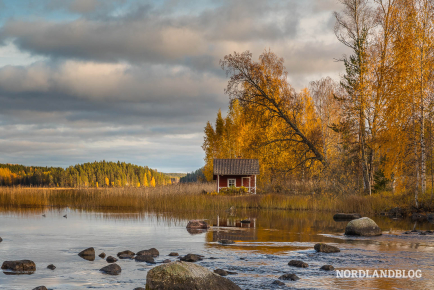 Kleines Fischerhaus an einem finnischen See im Herbstlicht 