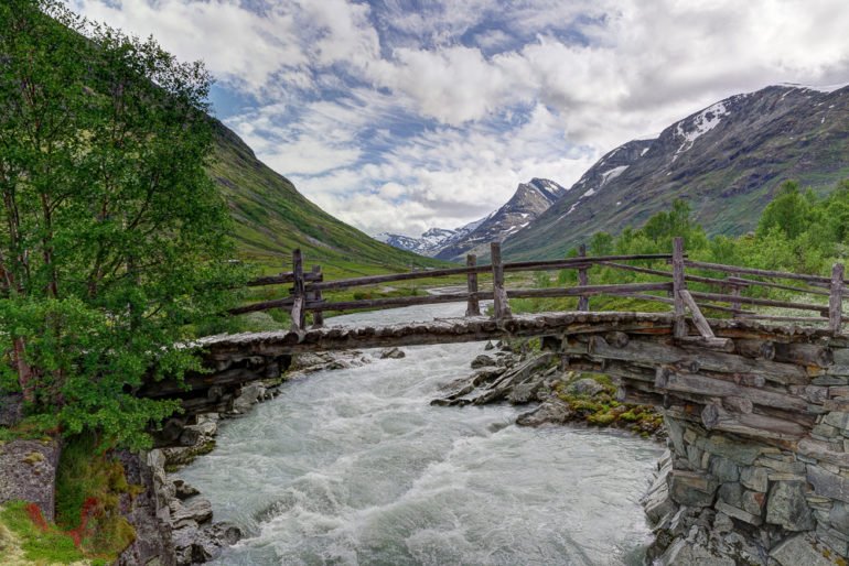 Bild von einer alten Brücke mit einem Fluss und Bergen in der Ferne im Jotunheimen, Norwegen