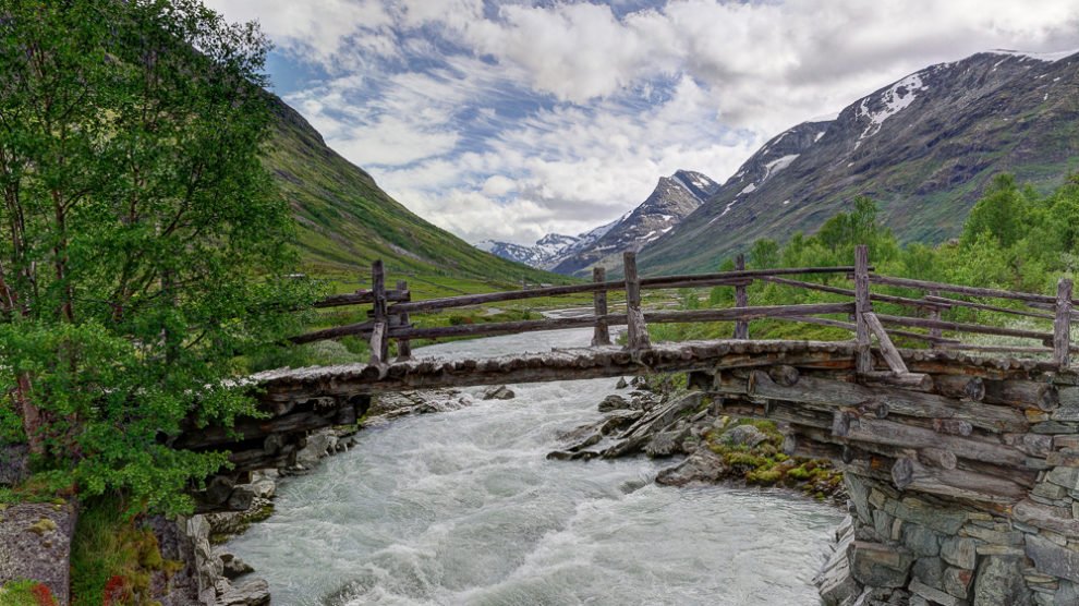 Bild von einer alten Brücke mit einem Fluss und Bergen in der Ferne im Jotunheimen, Norwegen